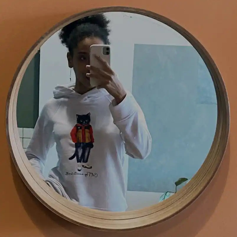 Round mirror reflecting a person in a cat-themed hoodie.