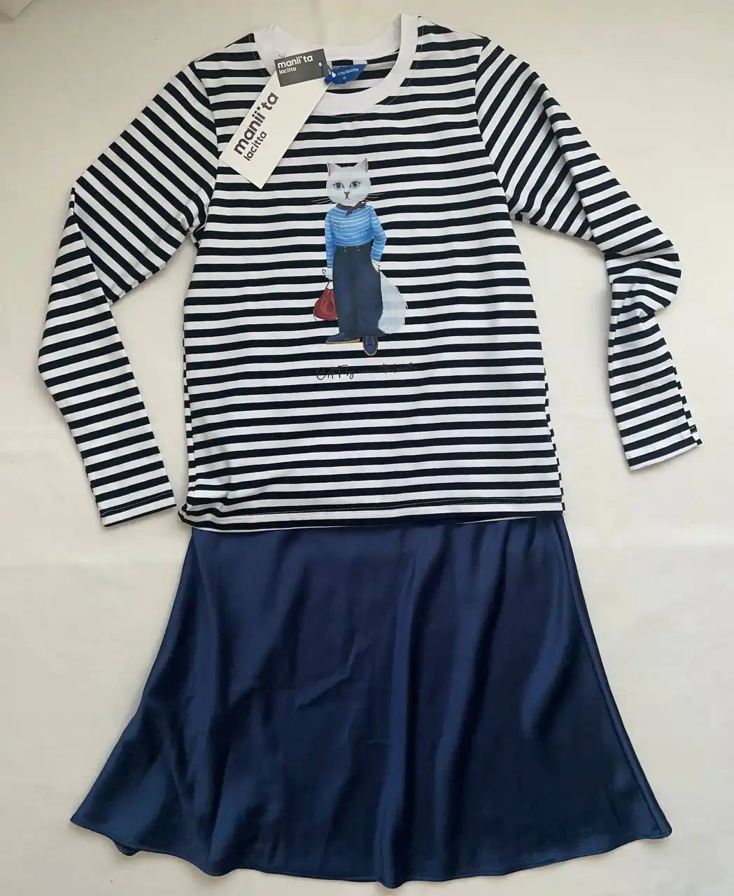 Striped long-sleeved shirt with cat graphic and navy skirt.