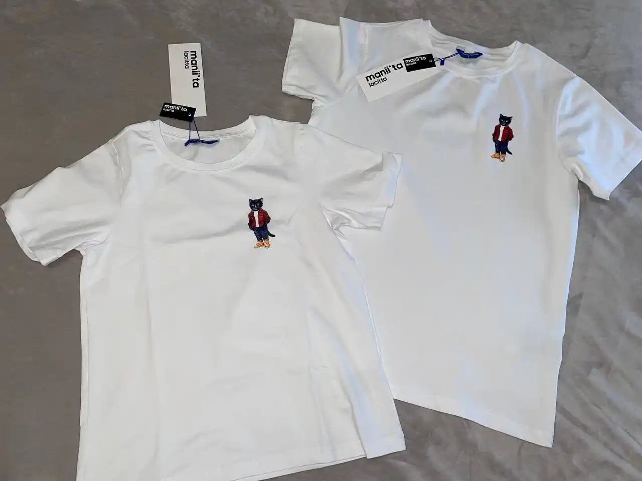 Two white t-shirts with cat embroidery.
